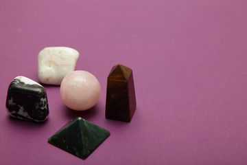 Magic stones and crystals of different shapes and colors lying in bulk on a bardic background.