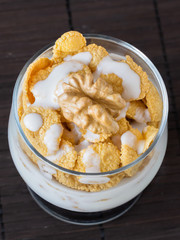 Yogurt with cornflakes and walnuts in a glass goblet
