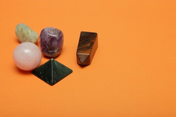 Magical stones and crystals of various shapes and colors lying loose on a yellow background