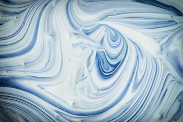 Empty abstract background for layouts. The process of mixing dark blue and white paint close-up. Photo with vignette.