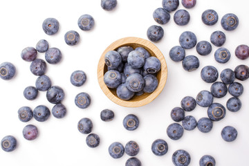 Lot of whole fresh sweet purple blueberry american with wooden bowl flatlay isolated on white background
