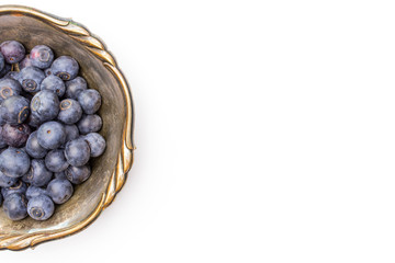 Lot of whole fresh sweet purple blueberry american in old iron bowl flatlay isolated on white background