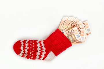 Traditional red Christmas sock stuffed with money on white background.  Concept of gifts, saving and hiding money in safe place.  