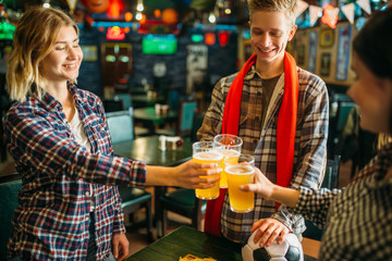 Football fans raise their glasses in sports bar