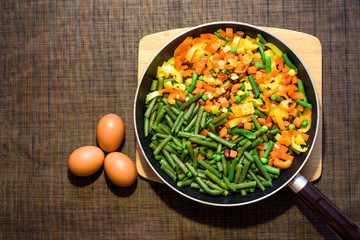 mix Fresh vegetables in a frying pan . fresh egg. celery stew, carrots, peas, bell peppers and tomatoes