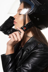 Fototapeta na wymiar Beautiful young sexy biker girl, wearing a black leather jacket bodysuit and a helmet on her head. Isolated on white background. Commercial and advertising design. Close up