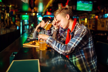 Sad fan covers face with hands in sports bar