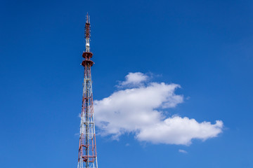 telecommunication radio tower on the vast blue sky background. White clouds on sky.