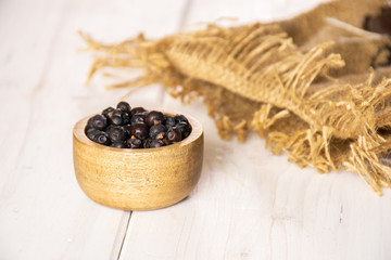 Lot of whole dry juniper berry seed on white wood