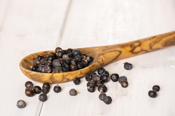 Lot of whole dry juniper berry seed on white wood