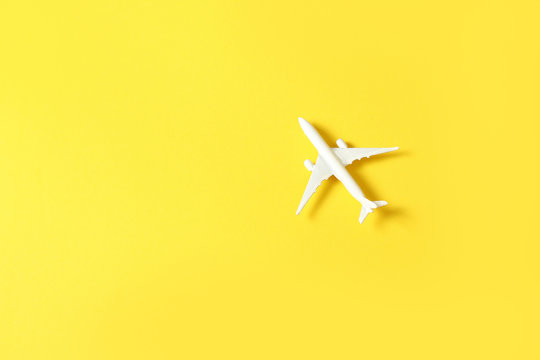 Miniature toy airplane on yellow background. Trip by airplane.