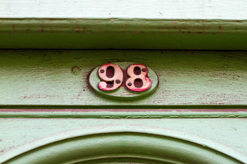 House number 98 with the ninety-eight in red on a green door frame