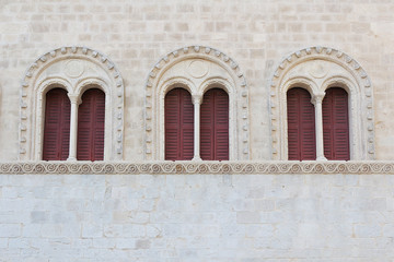 Antique arched windows in white stone wall