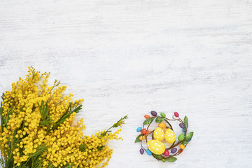 Easter background. Easter decoration and mimosa bouquet on white background. Top view, copy space.