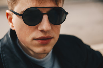 Portrait of a guy in round sunglasses and leather jacket