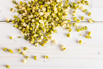 Lot of whole fresh green bean sprouts mungo flatlay on white wood