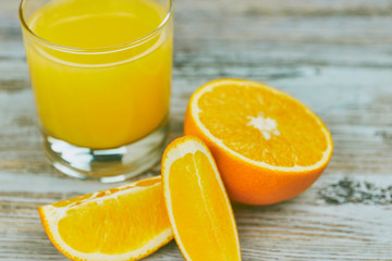 a glass of fresh orange juice with fresh citrus fruits on a light wooden table. horizontal view. citrus juice