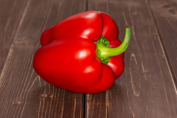 One whole bulgarian red bell pepper on brown wood