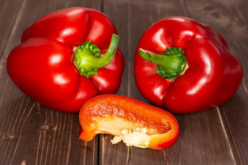 Group of two whole one slice of bulgarian red bell pepper on brown wood