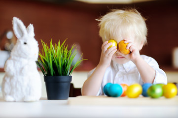 Cute toddler child hunting for easter egg on Easter day. Little boy celebrate Easter at home. 