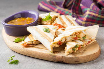 Mexican quesadilla with chicken, tomatoes, cheese and grilled sauce. Tasty snack in a pellet, healthy food