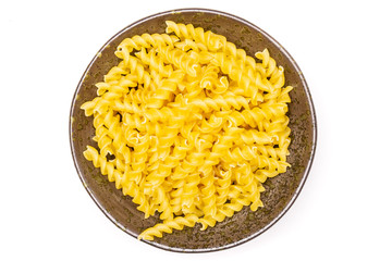 Lot of pieces of raw italitan yellow pasta torti in a grey ceramic bowl flatlay isolated on white...