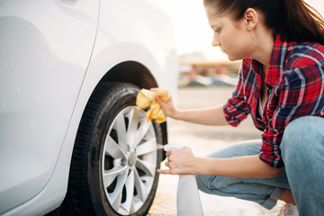 Fototapeta na wymiar Woman cleans wheel disk of the car with spray
