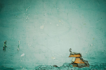 Wall with peeling paint and exposed bricks. Toned image.