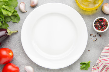 White plate in the middle, ingredients all around. Eggplant, tomatoes, cilantro, olive oil, spices. Preparation of caponata