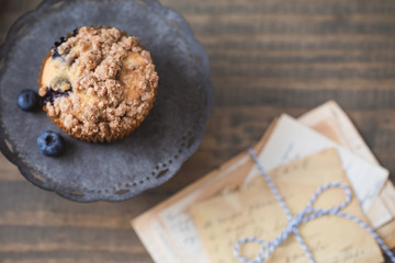 Homemade Blueberry Muffin Isolated on Tin Pedestal on Wooden Table Top; Vintage Recipe Cards beside the Muffin; 
