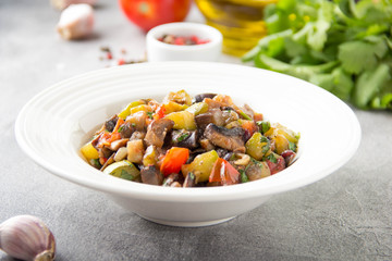 Vegetable stew with eggplant, zucchini, tomatoes, onions, mushrooms, garlic and cilantro. Vegetarian ajapsandali, Italian caponata. Traditional saute Ratatouille