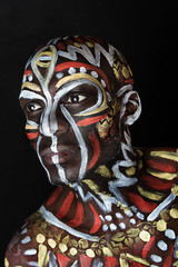 Close up portrait of strong emotional African-American guy. Ethnic African painting. Nigerian Body Art. Professional colorful makeup