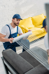 mover wrapping couch with roll of stretch film in apartment