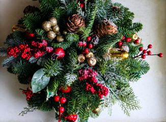 Naklejka na ściany i meble Christmas composition of pine branches, golden Christmas decorations, red berries and artificial snow.
