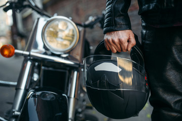 Biker in leather jacket with helmet in hand