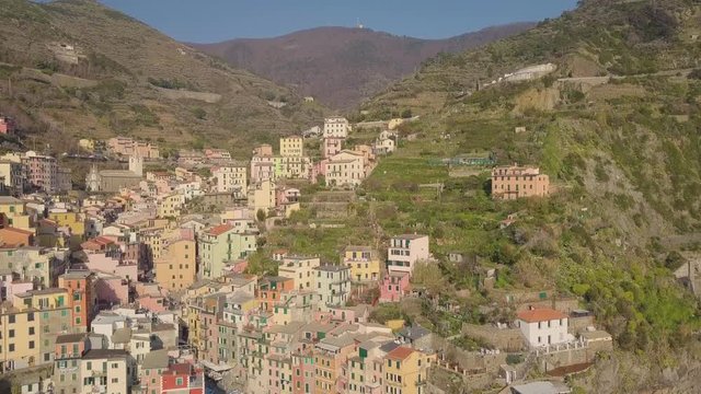Vacanze estive al mare in Liguria, il borgo delle Cinque terre chiamato Riomaggiore che si affaccia sul mare Mediterraneo a precipizio sugli scogli. Turismo, buon cibo e relax.