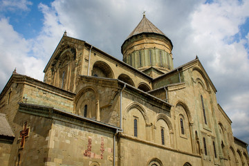 Fototapeta na wymiar Svetitskhoveli (life-giving pillar) is the cathedral patriarchal temple of the Georgian Orthodox Church. UNESCO heritage. Georgia, Mtskheta. Church, built with a tower and arches. Blue sky with clouds