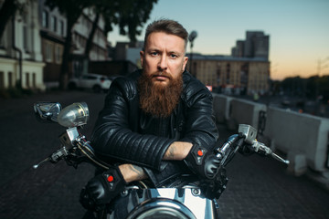 Fototapeta na wymiar Brutal bearded biker poses on chopper, front view