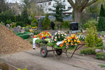Ein Karren voller Kränze vor dem Grab © Blende8