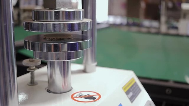 Machine performing a test by flat crushing a sample of corrugated cardboard in a factory
