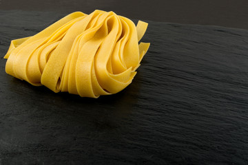 Raw yellow italian pasta fettuccine, fettuccelle or tagliatelle