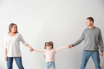 Divorced parents arguing about child custody on light background - obrazy, fototapety, plakaty