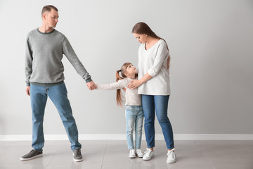 Unhappy family after divorce against light wall