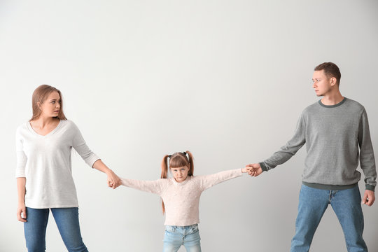 Divorced parents arguing about child custody on light background