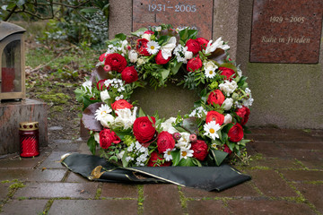 Schöner Kranz mit Schleife vor einem Urnengrab © Blende8