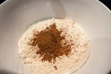 Woman is cooking in kitchen, baking a cake or pastry products. Flour and cocoa in a bowl. Raw,...