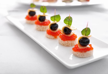 Plate with tasty canapes on table, closeup