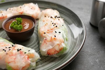 Plate with tasty spring rolls on grey table, closeup