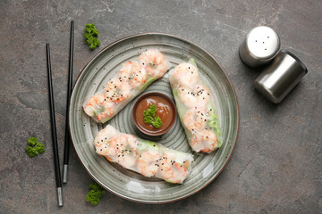 Plate with tasty spring rolls on grey background