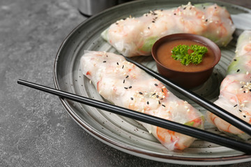 Plate with tasty spring rolls on grey table, closeup
